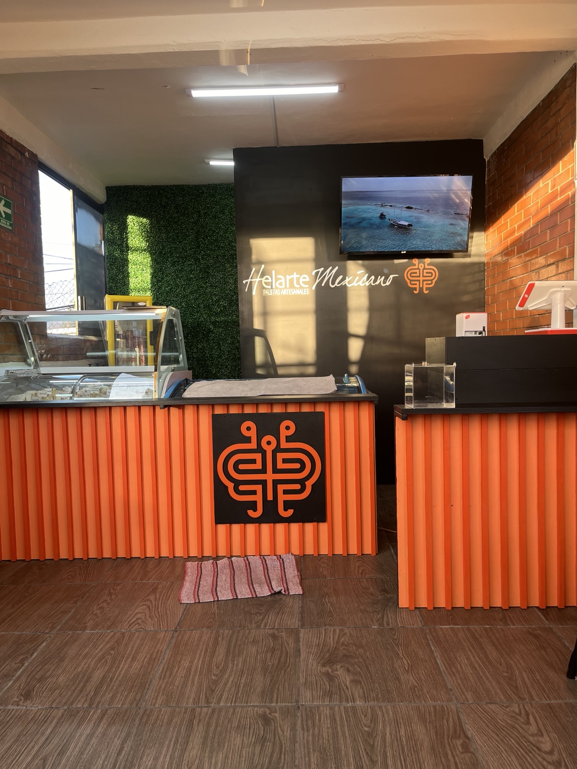 Mostrador de Helarte Mexicano con mobiliario naranja y el logotipo en la pared